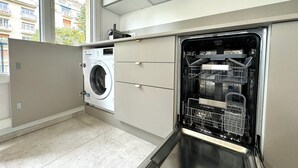 A compact kitchen with a built-in washer and dishwasher, large windows, and a view of the city.