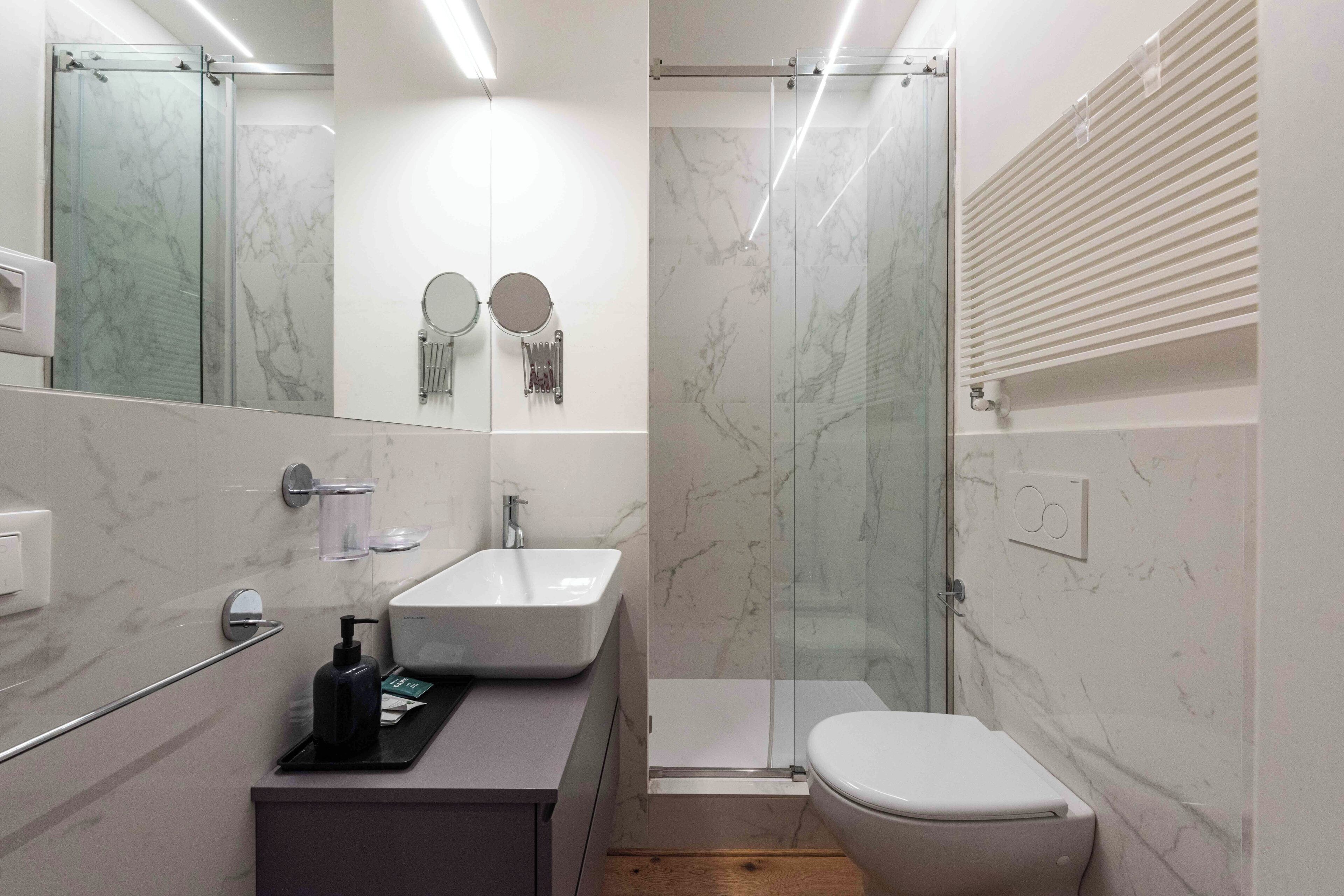 A modern bathroom with a glass shower enclosure, a white sink, and a toilet.