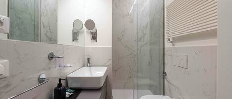 A modern bathroom with a glass shower enclosure, a white sink, and a toilet.