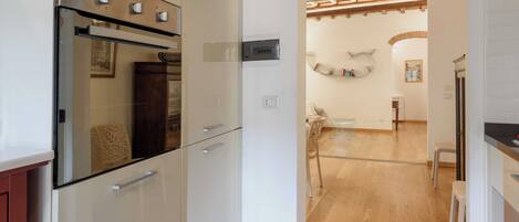 Een moderne keuken met witte kasten, een ingebouwde oven en een houten plafond.