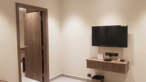 Un bagno moderno con una porta in legno, una TV a muro e uno scaffale in legno con un lavandino.