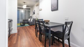 Un espace repas moderne avec une table et des chaises en bois, un canapé et une grande fenêtre.