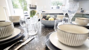 A dining table set with plates, bowls, glasses, and a pitcher of water.
