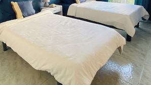 Une chambre d’hôtel avec deux lits, une table de chevet, une lampe et une grande fenêtre avec des rideaux.