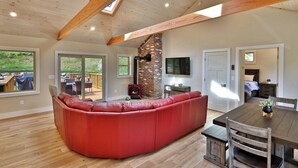 A spacious living area with a red sectional sofa, a brick fireplace, and a dining table with chairs. - Experience the charm of Peak Hill Home,  Entire home in Killington/Pittsfield, Vermont (Pittsfield)