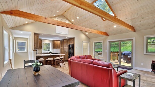 A spacious living area with a red sectional sofa, a wooden dining table, and a kitchen in the background. - Experience the charm of Peak Hill Home,  Entire home in Killington/Pittsfield, Vermont (Pittsfield)