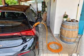 A car parked inside a garage with a charging cable connected to it. - Villa Salamander Suite - Garden & EV Charger (Komen)