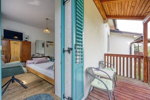 Une chambre Ă coucher avec un lit, un bureau, une chaise et un balcon.