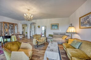 Un vaste salon agrĂ©mentĂ© dâun lustre, dâun canapĂ©, dâun fauteuil et dâun coin repas avec une table et des chaises.