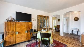 A dining area with a wooden cabinet, a television, and a dining table with chairs.