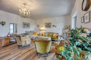 A living room with a chandelier, sofas, a table, and a potted plant.
