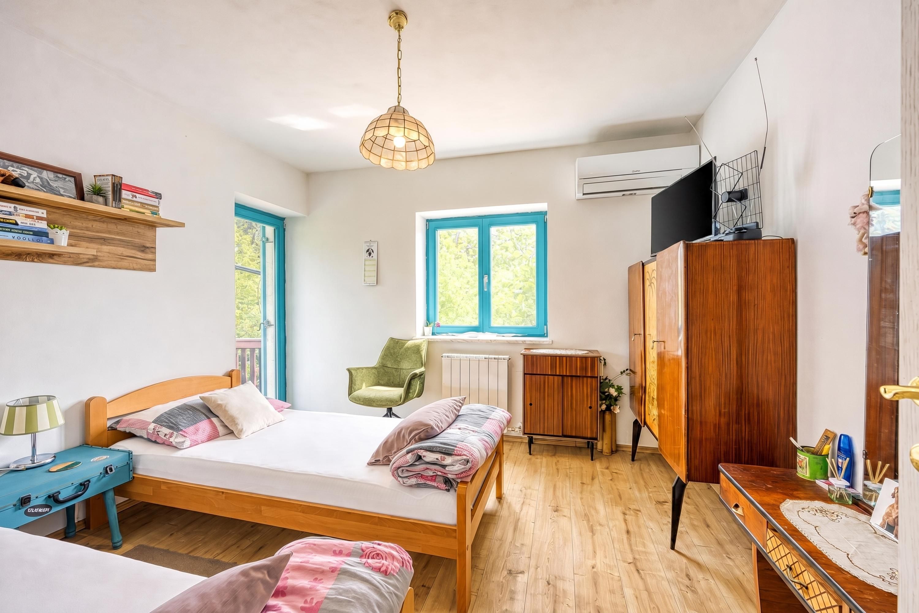 A bedroom with a wooden bed, a desk, a chair, a wardrobe, and a window with blue shutters.