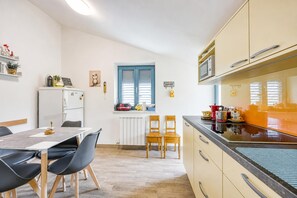 A modern kitchen with a dining table, chairs, and a microwave. - Villa Salamander Suite - Garden & EV Charger (Komen)