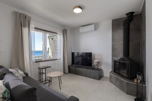 A modern living room with a sofa, a small table, a TV, and a fireplace.