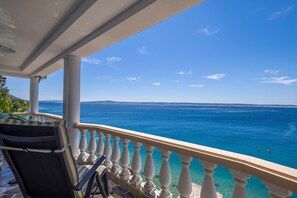 A balcony with a view of the sea, a chair, and a table. - Holiday Home Seafront Escape (Starigrad)