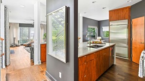 Une cuisine moderne dotée d’un grand îlot central, de meubles en bois et d’un réfrigérateur en acier inoxydable.