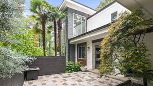 Une maison moderne dotée d’un patio avec un sol en pierre, une petite piscine et diverses plantes.