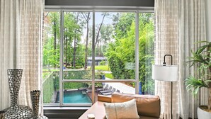 Un salon moderne avec une grande fenêtre, un canapé, une lampe et des vases décoratifs.