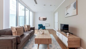 A modern living room with a sofa, coffee table, and TV stand. - The Ealing Luxury Flat (London)