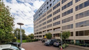 A modern multi-story building with a parking area in front. - The Ealing Luxury Flat (London)