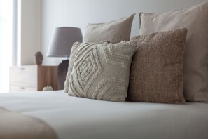 A bed with two pillows, a lamp, and a nightstand. - The Ealing Luxury Flat (London)