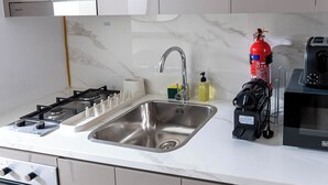 A kitchen with a stainless steel sink, a gas stove, a microwave, and a built-in washing machine. - Nasma Holiday Homes - Azizi Riviera 41 (Dubai)