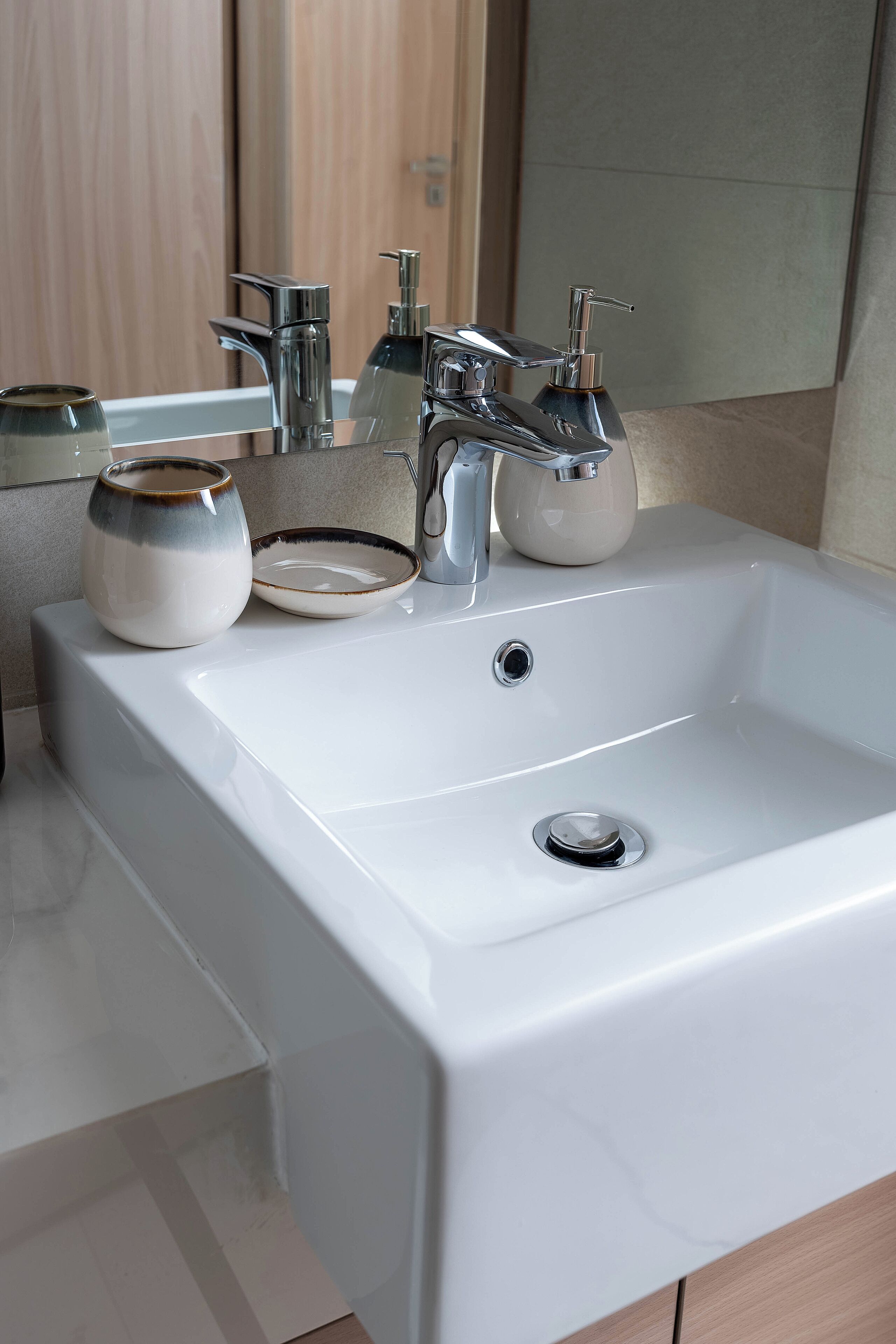 A modern bathroom sink with a chrome faucet, a soap dispenser, and a ceramic bowl.