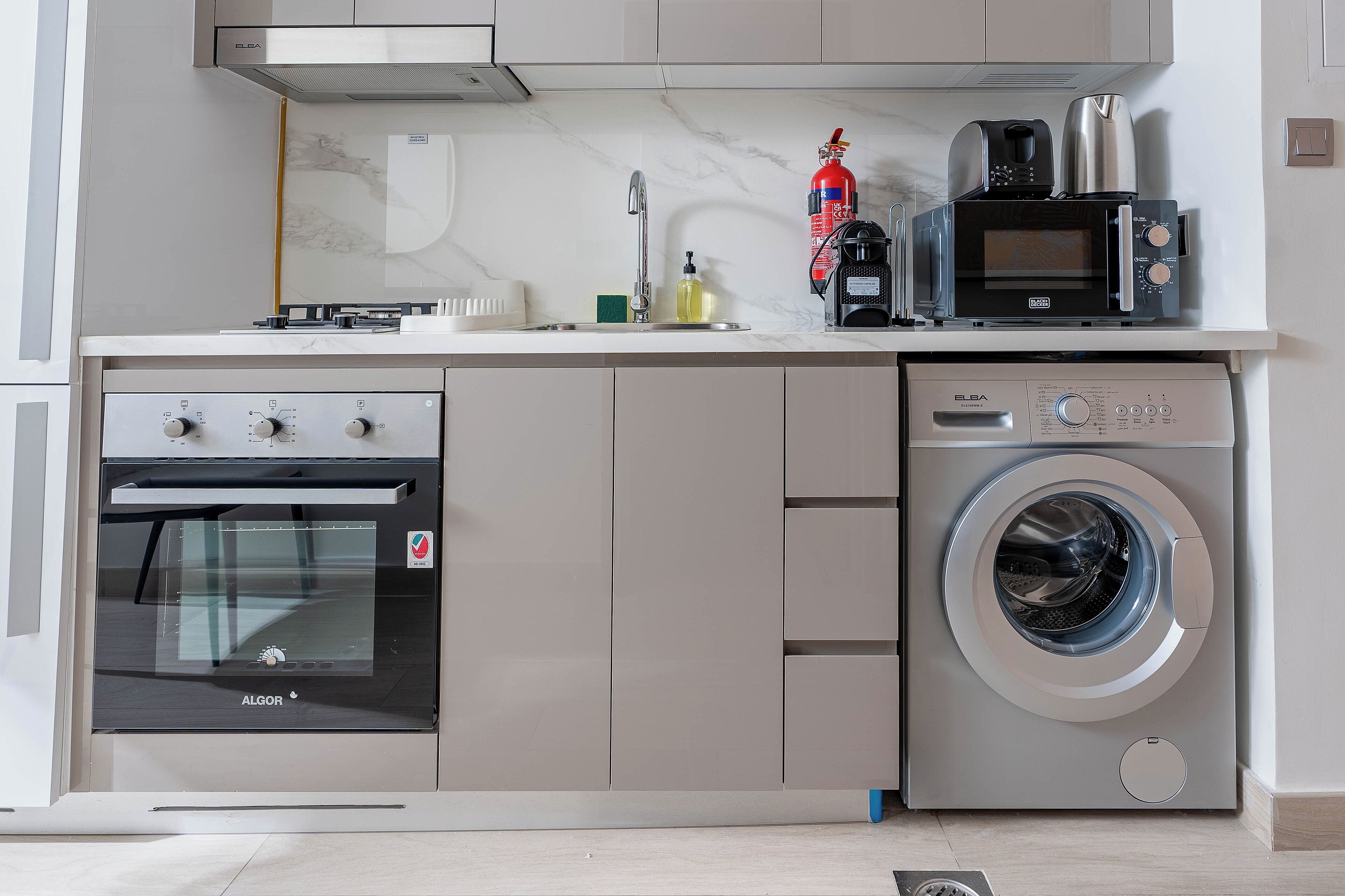 Eine kleine Küche mit Backofen, Mikrowelle und Waschmaschine.
