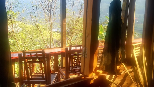 Una stanza con vista su alberi e un balcone.