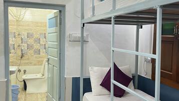 Una camera compatta con letti a castello, bagno con doccia e pavimento piastrellato.