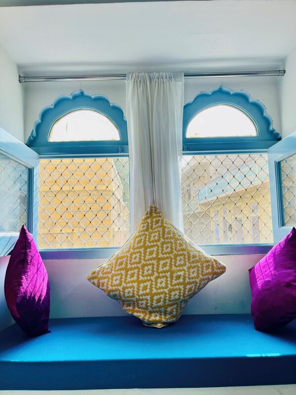 A window seat with two cushions, a white curtain, and a lattice-patterned window. - Jaisalmer Hostel Crowd (Jaisalmer)