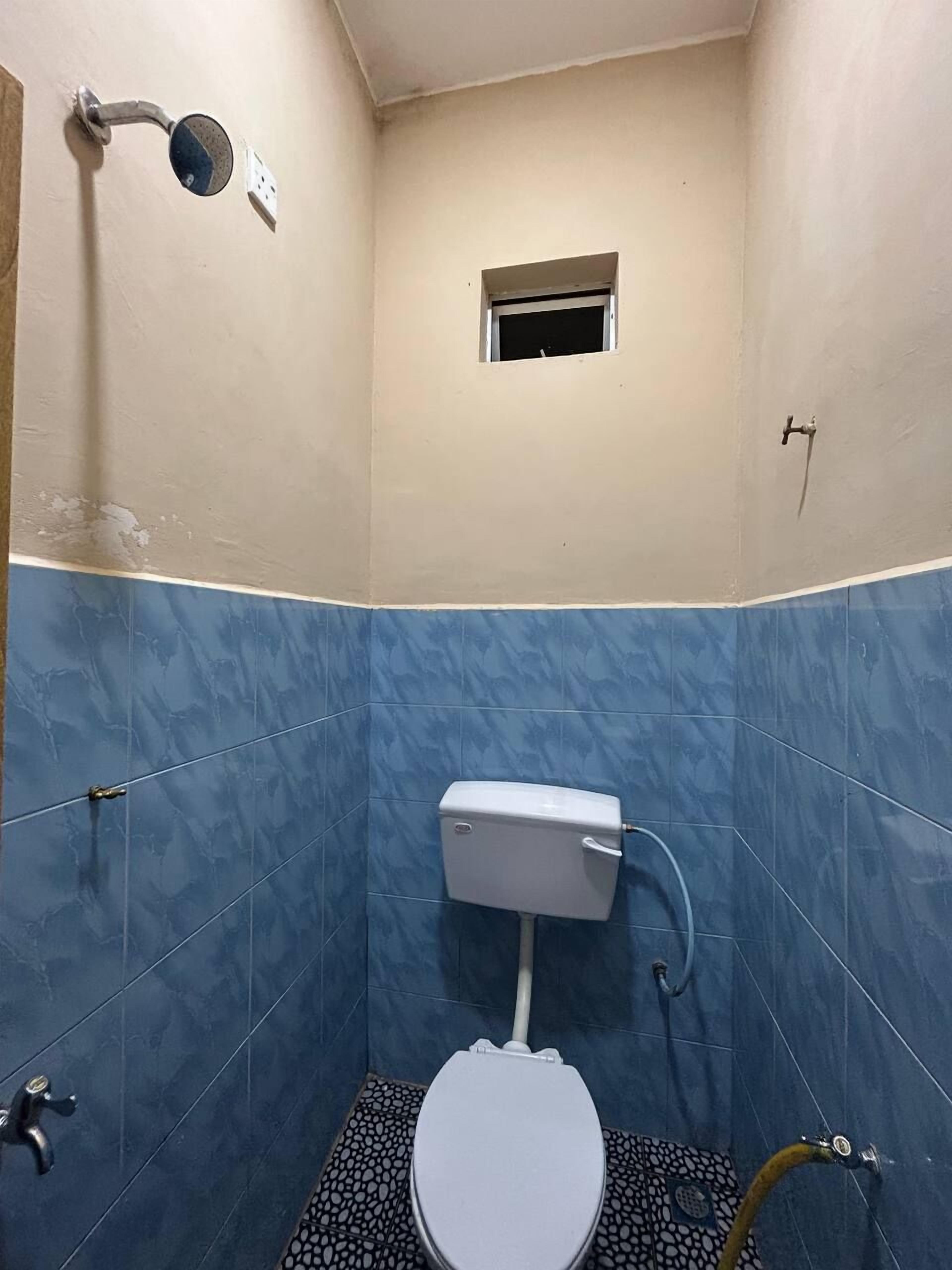 A small bathroom with a toilet, a shower, and a window.