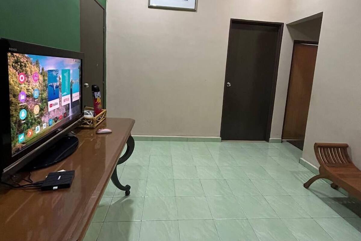 A reception area with a television, a framed picture on the wall, and a bench.