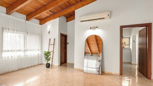 Een ruime kamer met een houten plafond, een grote spiegel en een plant in pot.