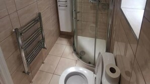 A bathroom with a toilet, a glass shower enclosure, and a towel rack. - City Apartment Sleeps 4 With Garden (Romford)