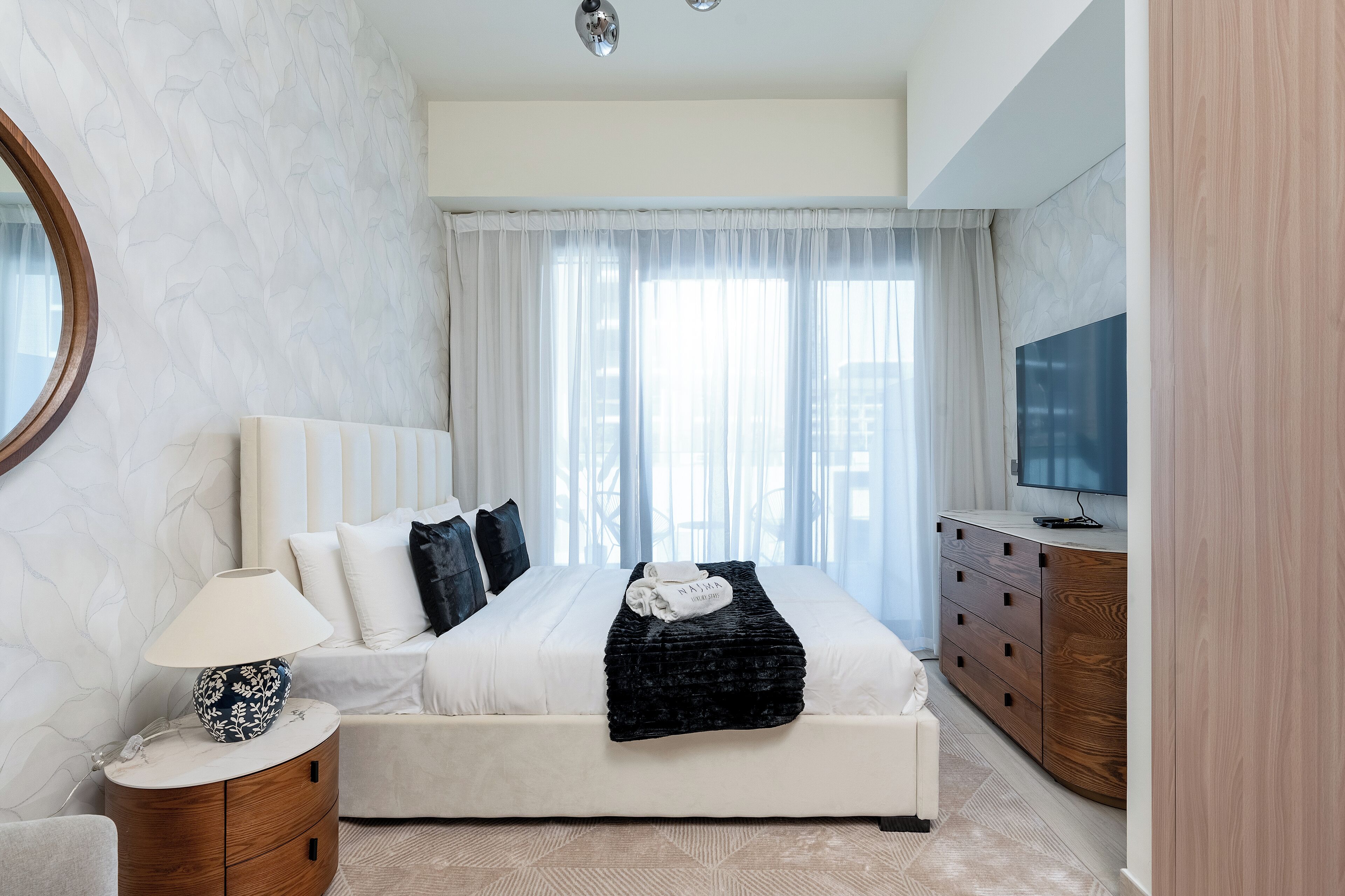 Ein modernes Schlafzimmer mit einem großen Bett, einem Nachttisch, einem Fernseher und einem Holzschrank.