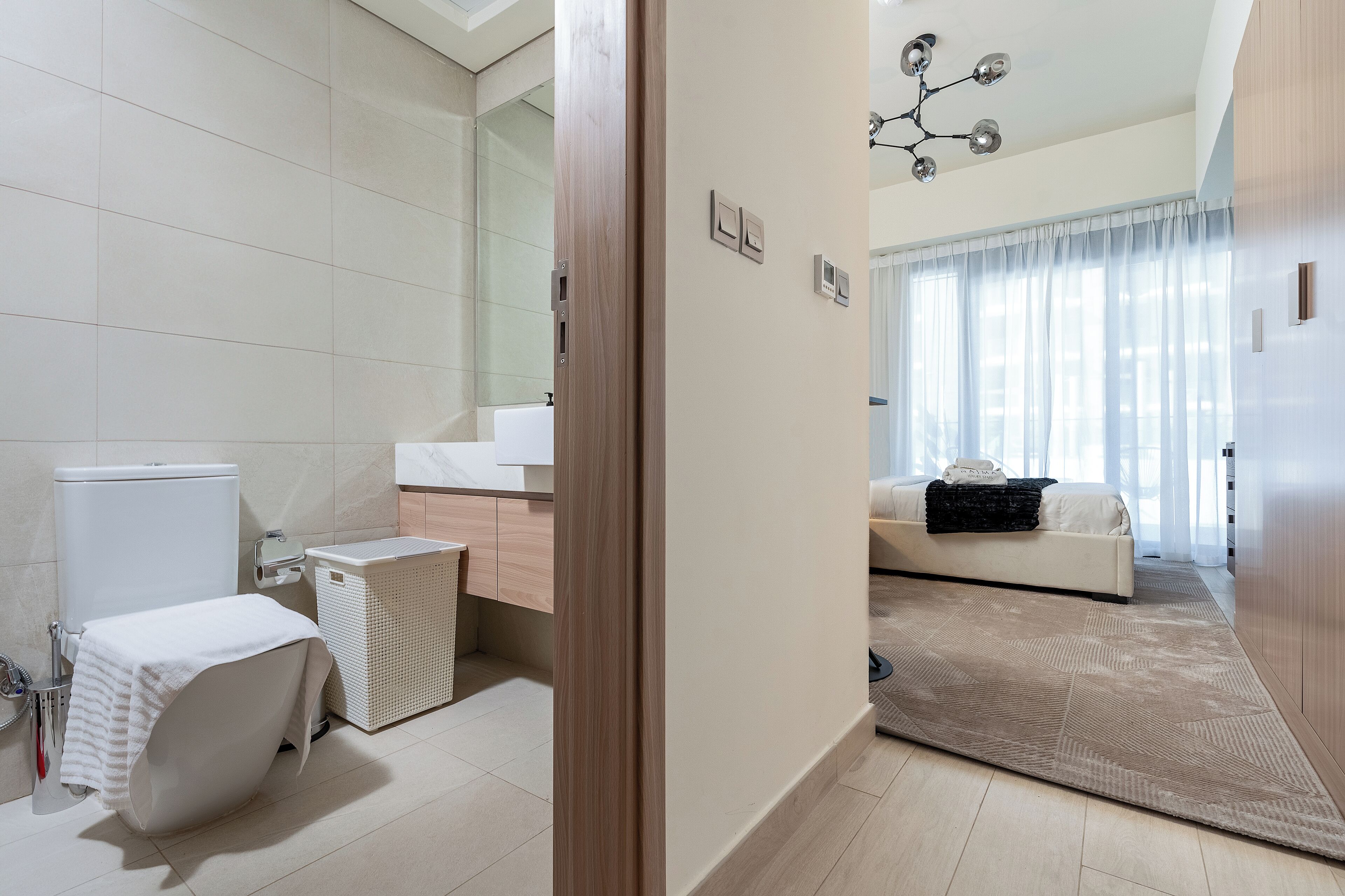 A modern bathroom with a toilet, bidet, and a white laundry basket.