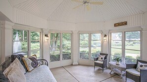 A sunroom with a curved ceiling, large windows, a bed, and seating area. - Klinger Lake Cove - Sleeps 16-24 (White Pigeon)