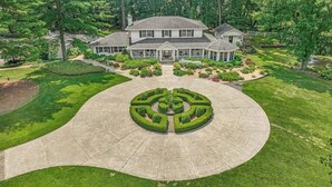A large, two-story house with a well-maintained lawn and a circular driveway leading to a gated entrance. - Klinger Lake Cove - Sleeps 16-24 (White Pigeon)