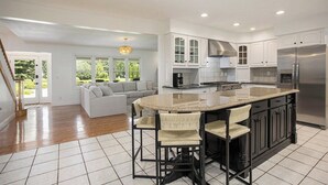 A spacious kitchen with a large island, white cabinetry, and a stainless steel refrigerator. - Klinger Lake Cove - Sleeps 16-24 (White Pigeon)