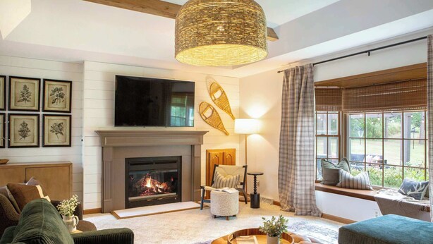 A cozy living room with a fireplace, comfortable seating, and a large window with curtains. - The Baraboo Hideaway (Baraboo)