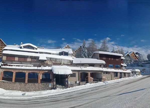 A snow-covered building with a stone facade, multiple windows, and a clear sky. - Chalet le Alpi (Frabosa Sottana)