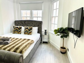 Relax in a serene bedroom with a large bed, tufted headboard, and plush bench.