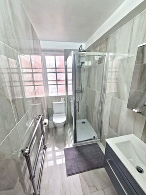 Bathroom features a glass-enclosed shower, bathtub, and toilet.