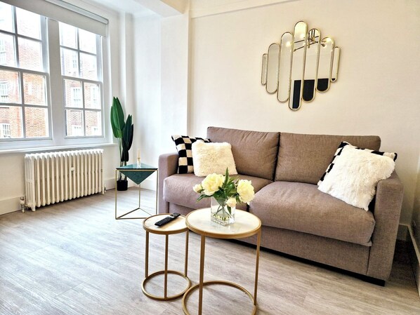 Relax in this stylish living room with a sofa, coffee table, and side table, offering a view of the city.