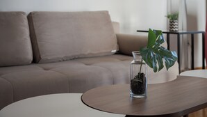 A living room with a sofa, a coffee table, and a potted plant. - Athenian Heritage Residences (Athens)