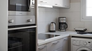 A modern kitchen with stainless steel appliances, a built-in oven, a coffee maker, and a washing machine. - Athenian Heritage Residences (Athens)