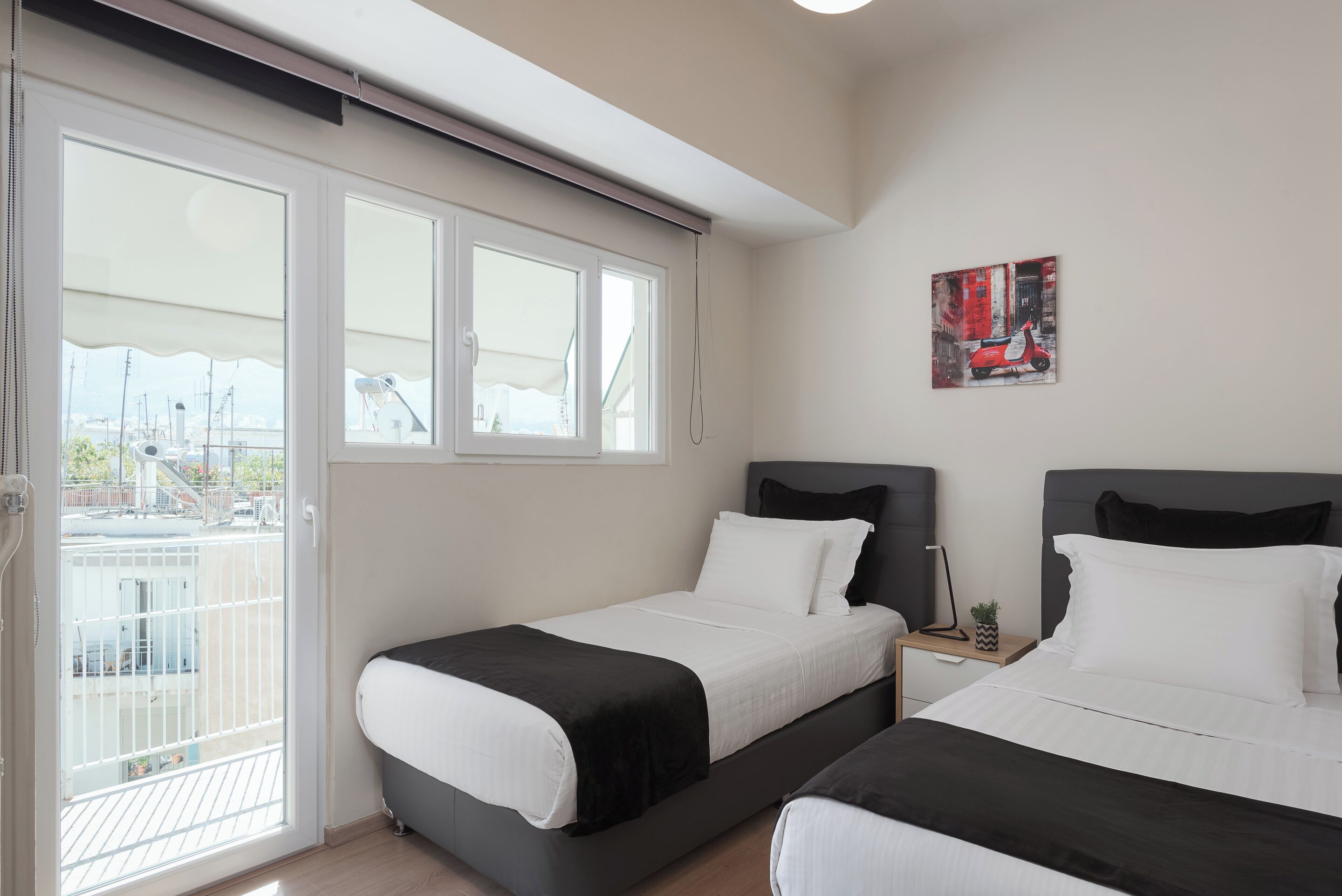 A hotel room with two beds, a balcony, and a painting on the wall.