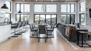 A modern kitchen with a dining area, large windows, and a loft-style ceiling. - Spa & Mountain View | Le Eastmain View (Saint-Côme)