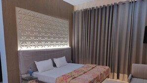 Ein modernes Schlafzimmer mit einem großen Bett, einem Nachttisch, einem Glastisch und einem eingelassenen Kopfteil mit geometrischem Muster.